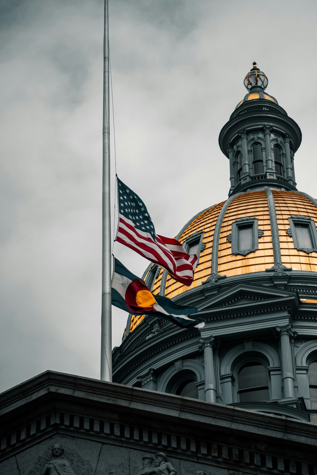 US and Colorado flag flying above legislature building